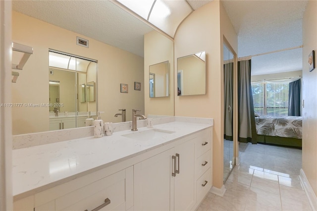 bathroom with tile patterned floors, vanity, and a textured ceiling