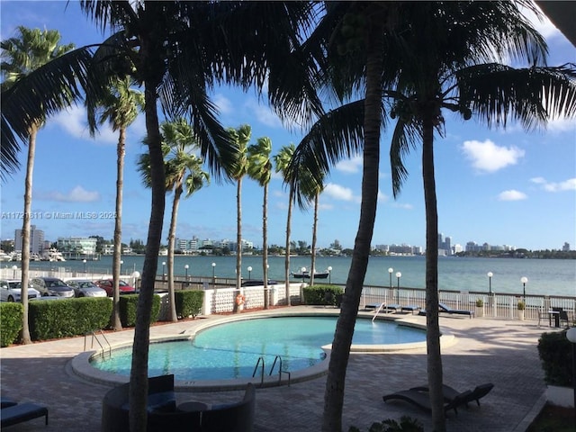 view of pool featuring a patio area and a water view