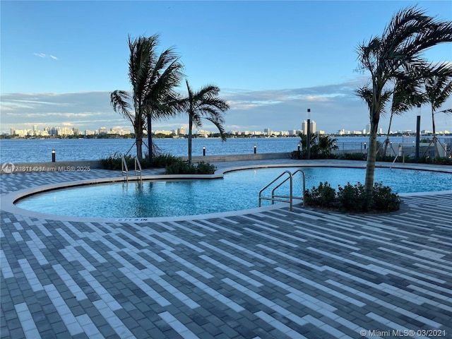 view of swimming pool with a patio area and a water view