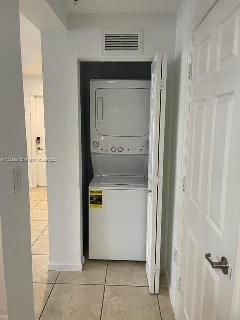 clothes washing area featuring stacked washer and clothes dryer and light tile patterned flooring