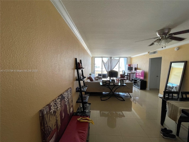 living room featuring tile patterned flooring, ceiling fan, ornamental molding, and a textured ceiling