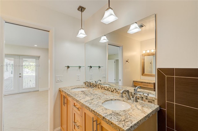 bathroom featuring french doors, vanity, and tasteful backsplash