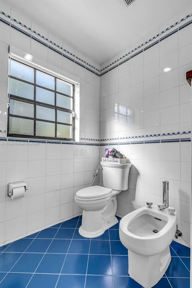 bathroom with tile patterned flooring, toilet, tile walls, and a wealth of natural light