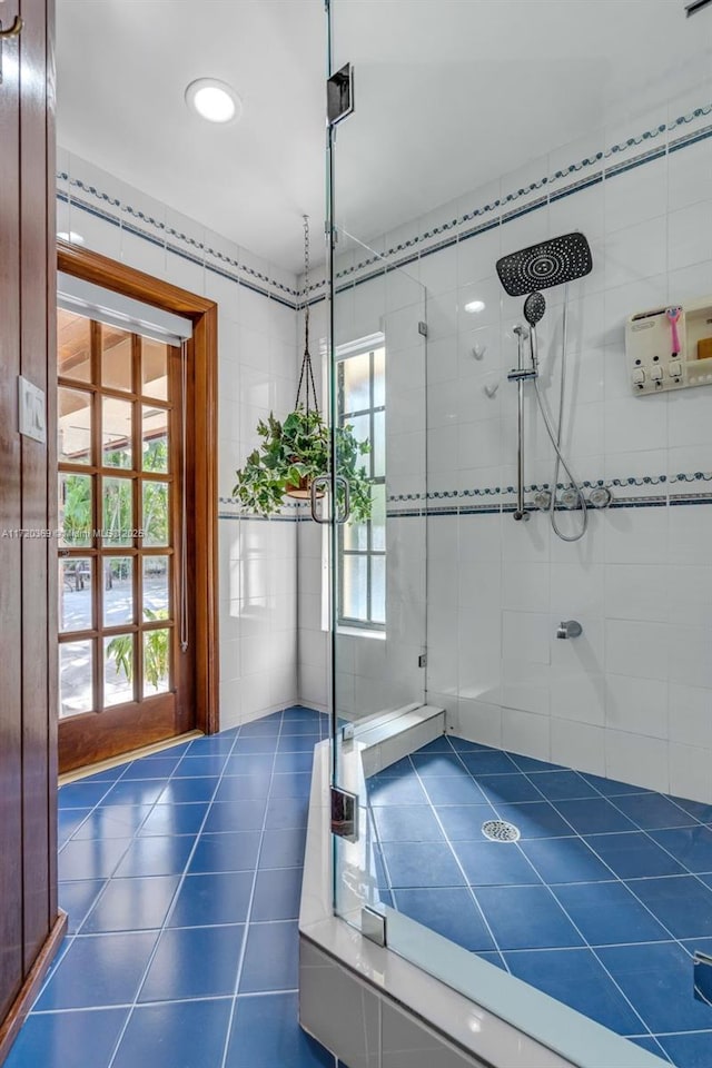 doorway to outside with dark tile patterned floors and tile walls