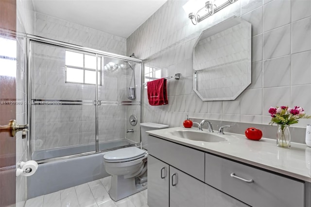 full bathroom featuring a wealth of natural light, vanity, tile walls, and enclosed tub / shower combo