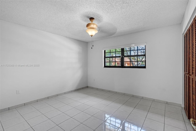 spare room featuring ceiling fan, light tile patterned flooring, and a textured ceiling