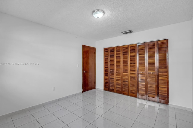 unfurnished bedroom featuring light tile patterned floors, a textured ceiling, and a closet