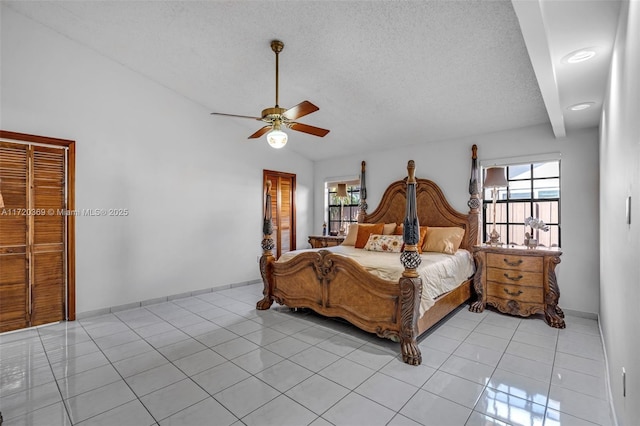 bedroom with lofted ceiling, ceiling fan, a textured ceiling, light tile patterned flooring, and a closet