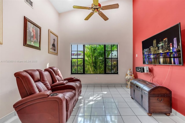 living room with ceiling fan, light tile patterned floors, and a high ceiling