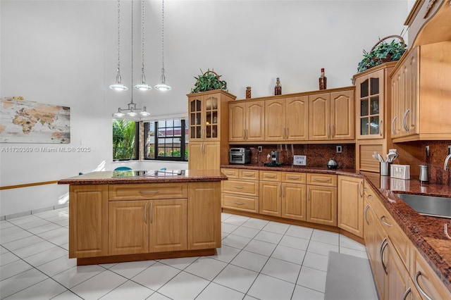 kitchen featuring dark stone countertops, sink, light tile patterned floors, and decorative light fixtures