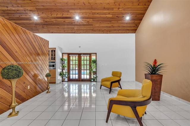 living area featuring french doors, wood ceiling, wooden walls, light tile patterned floors, and high vaulted ceiling