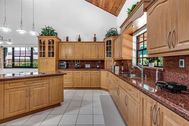 kitchen with pendant lighting, high vaulted ceiling, dark stone counters, sink, and decorative backsplash