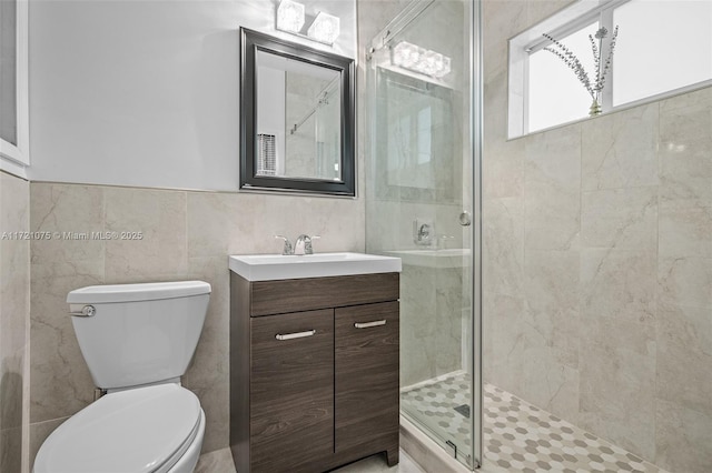 bathroom with an enclosed shower, vanity, toilet, and tile walls