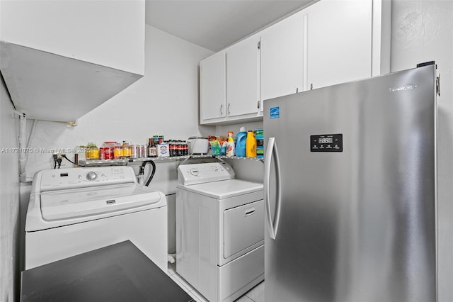 clothes washing area with washing machine and clothes dryer and cabinets