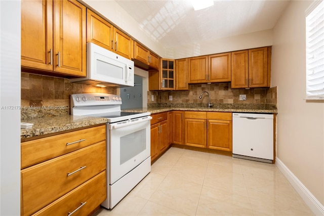 kitchen with sink, backsplash, light stone counters, and white appliances