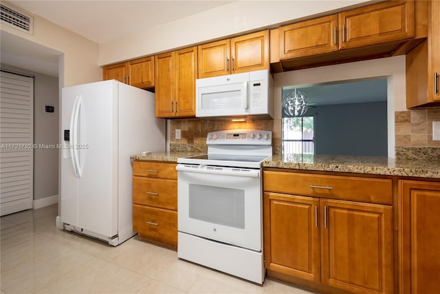 kitchen featuring light stone countertops, white appliances, a notable chandelier, and tasteful backsplash