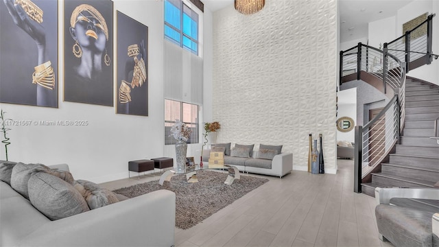 living room featuring plenty of natural light, a towering ceiling, and light hardwood / wood-style floors