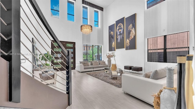 living room featuring hardwood / wood-style floors, a towering ceiling, and an inviting chandelier