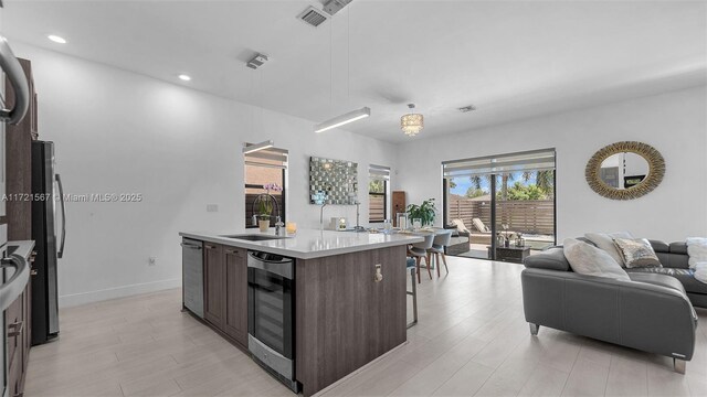 kitchen with wall oven, dark brown cabinets, sink, decorative light fixtures, and a kitchen island