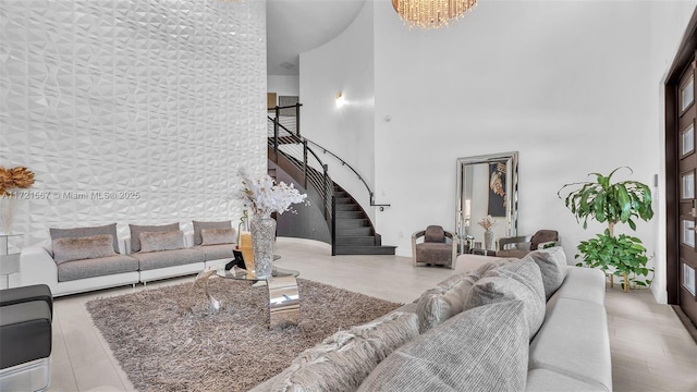 living room featuring a notable chandelier, a towering ceiling, and light hardwood / wood-style flooring