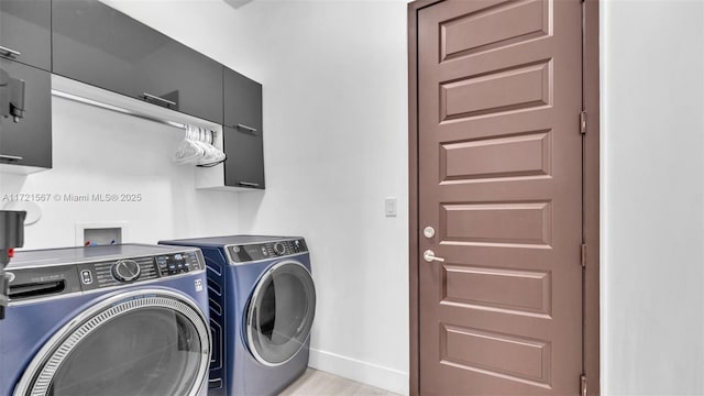 clothes washing area featuring cabinets and washing machine and dryer