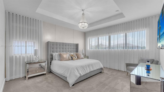 carpeted bedroom with a chandelier and a tray ceiling