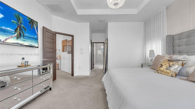 bedroom with a chandelier, light colored carpet, a raised ceiling, and ensuite bathroom