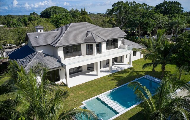 rear view of house featuring a yard, a balcony, and a patio