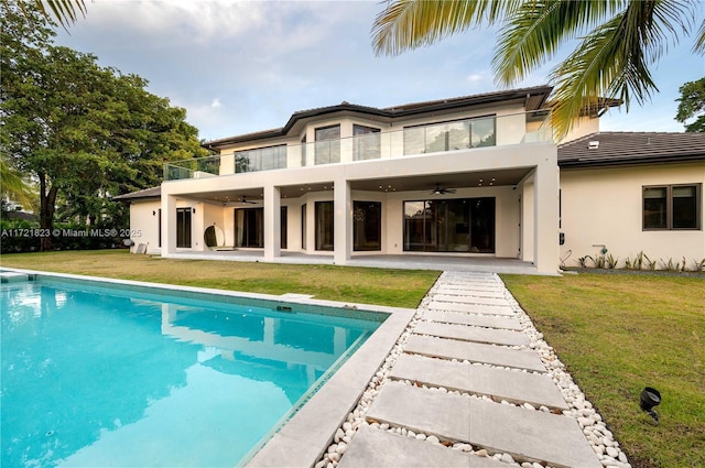 rear view of house featuring ceiling fan, a yard, a balcony, and a patio area