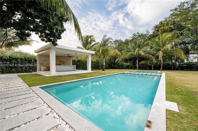 view of pool with a patio, a yard, and ceiling fan