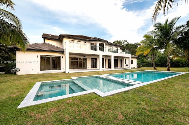 rear view of house with ceiling fan, a yard, a patio area, and a balcony