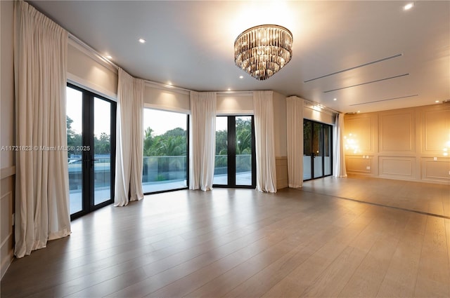 unfurnished room with an inviting chandelier, hardwood / wood-style flooring, and french doors