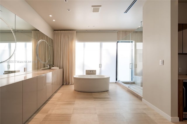 bathroom featuring plenty of natural light, shower with separate bathtub, and vanity