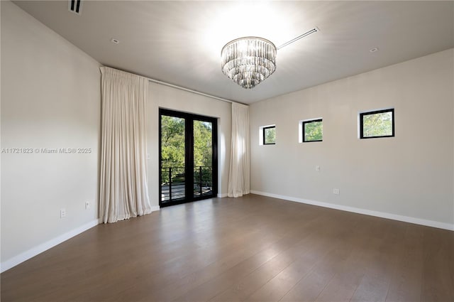 spare room with french doors, dark hardwood / wood-style floors, and a chandelier