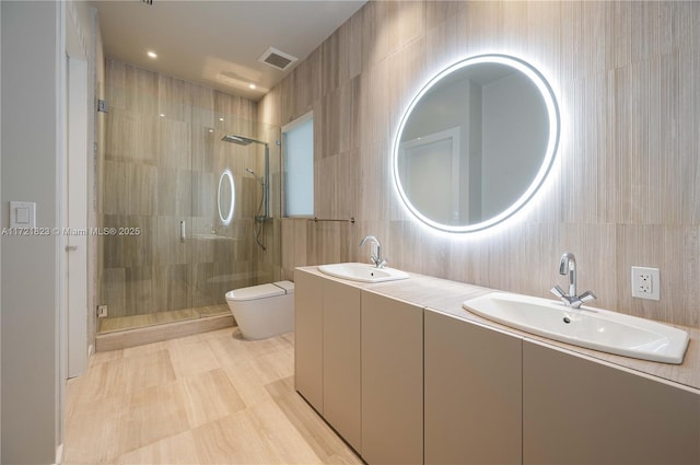 bathroom featuring tile walls, vanity, a shower with shower door, and toilet