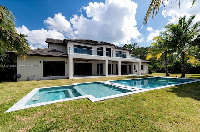 rear view of property with a yard, a patio, and a balcony