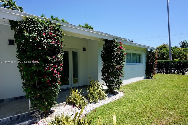 view of side of property with a lawn and stucco siding