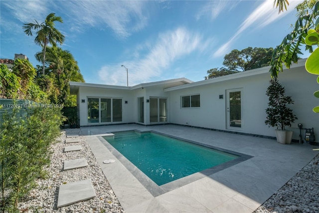 rear view of house with a patio area, fence, an outdoor pool, and stucco siding