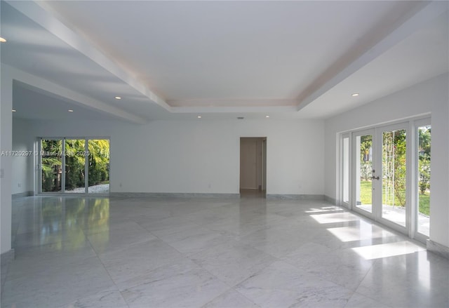 empty room featuring recessed lighting, baseboards, a raised ceiling, and french doors