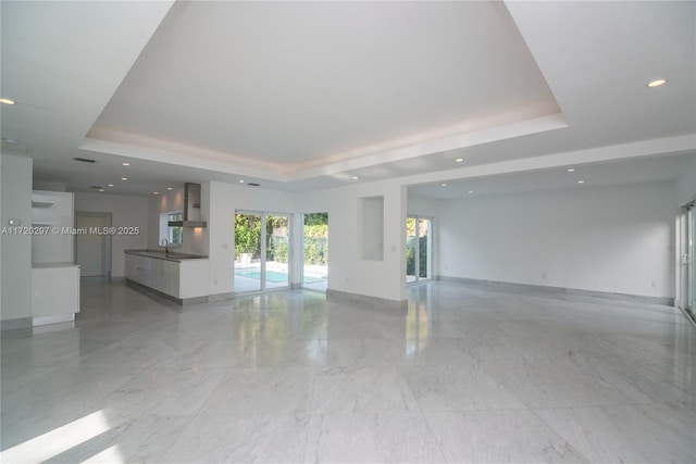 unfurnished living room with a tray ceiling, french doors, baseboards, and recessed lighting