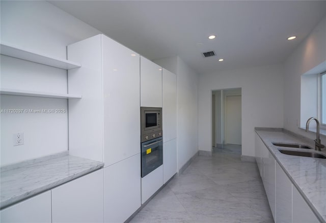 kitchen featuring black oven, open shelves, modern cabinets, and a sink