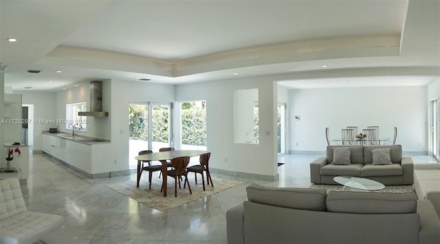 living room with recessed lighting, a raised ceiling, marble finish floor, and baseboards