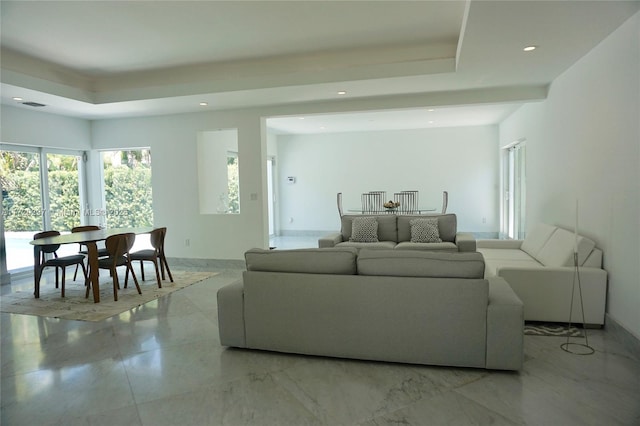 living room with baseboards, a tray ceiling, and recessed lighting