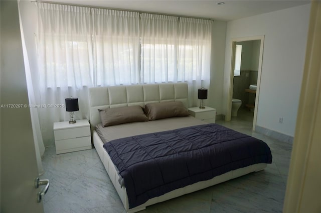 bedroom featuring marble finish floor, connected bathroom, and baseboards