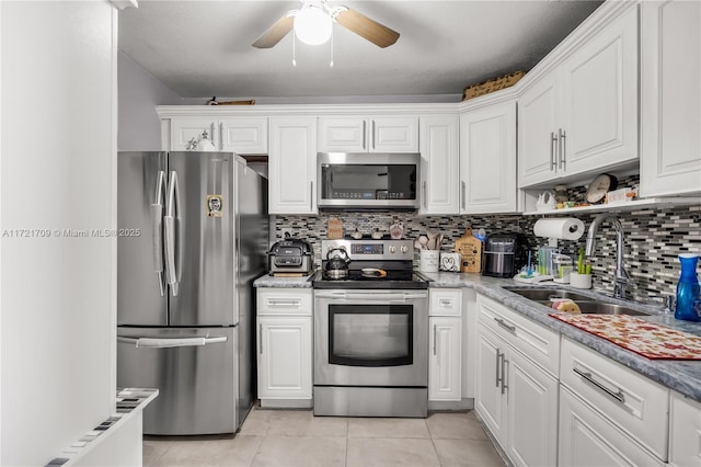 kitchen featuring appliances with stainless steel finishes, tasteful backsplash, sink, white cabinets, and light tile patterned flooring