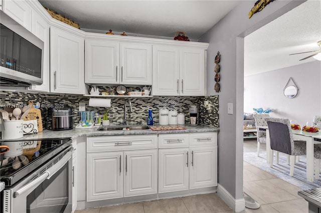 kitchen featuring white cabinetry, sink, light tile patterned flooring, and appliances with stainless steel finishes