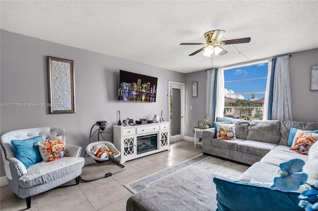 living room with ceiling fan, light tile patterned flooring, a textured ceiling, and a fireplace