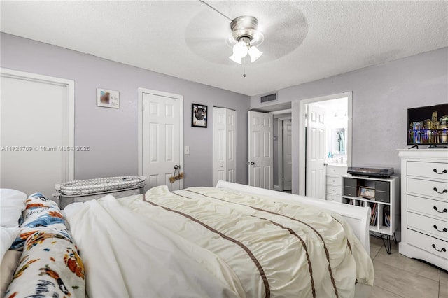 tiled bedroom featuring connected bathroom, ceiling fan, and a textured ceiling