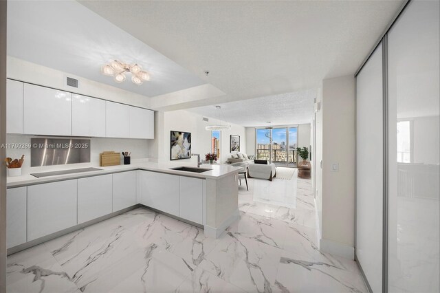 kitchen featuring sink, white cabinetry, a textured ceiling, black electric cooktop, and kitchen peninsula