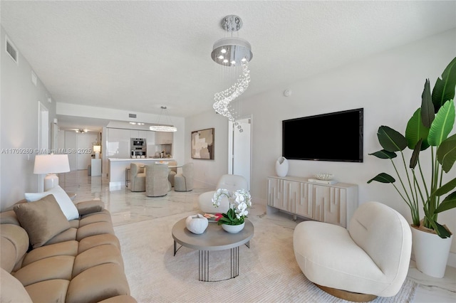 living area with a textured ceiling, marble finish floor, and visible vents